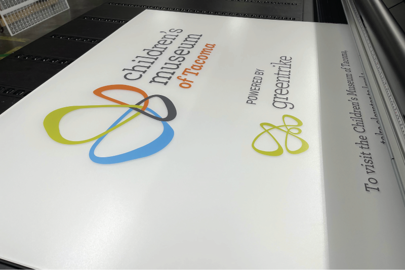 Printed white rigid sign panel with the Children's Museum of Tacoma logo and sponsor mark