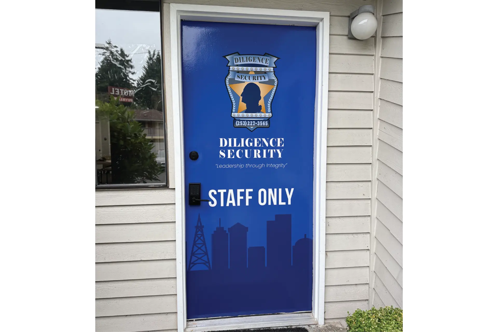 Blue printed door wrap with a security crest, staff-only wayfinding text, and skyline graphic