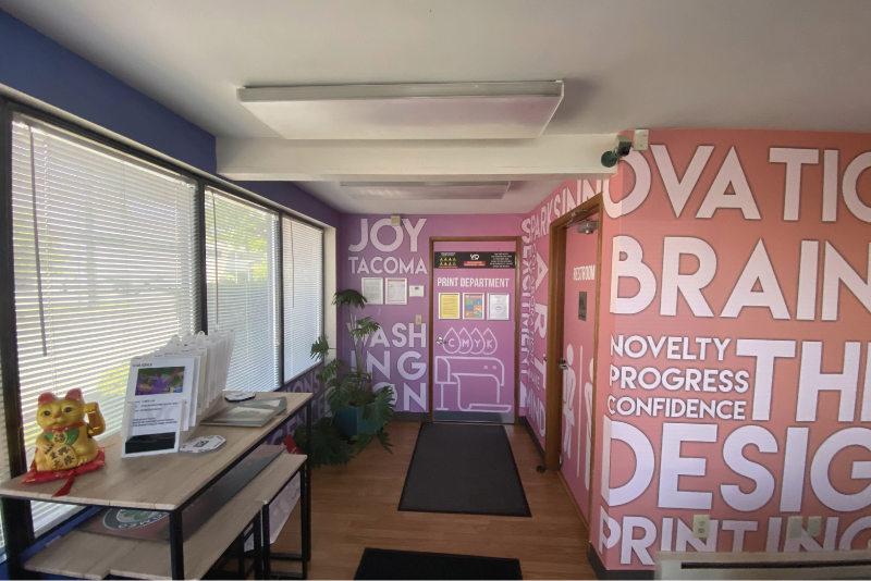 Print shop lobby with large pink and purple typographic wall graphics and department door signage