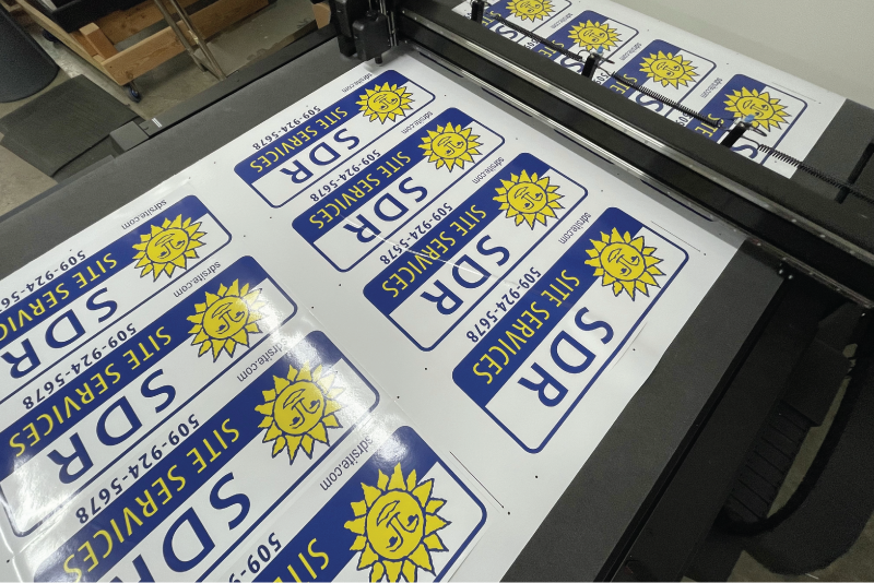Sheet of printed blue and yellow fleet decals on a flatbed cutting table