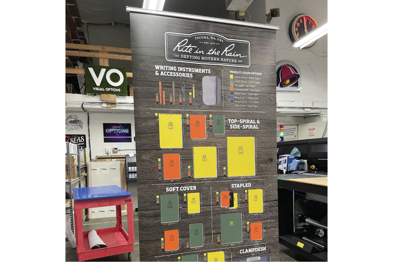 Tall retractable retail banner displaying a notebook product line with color options