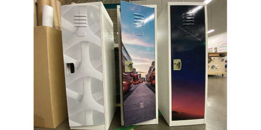 Three lockers side by side with printed vinyl wraps showing a city street scene and a gradient sky