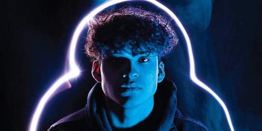 Creative portrait of a young man lit by a curved neon tube in blue and magenta light