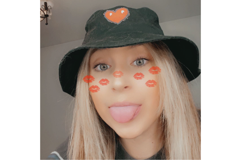 Person wearing a black bucket hat with an orange applique heart patch