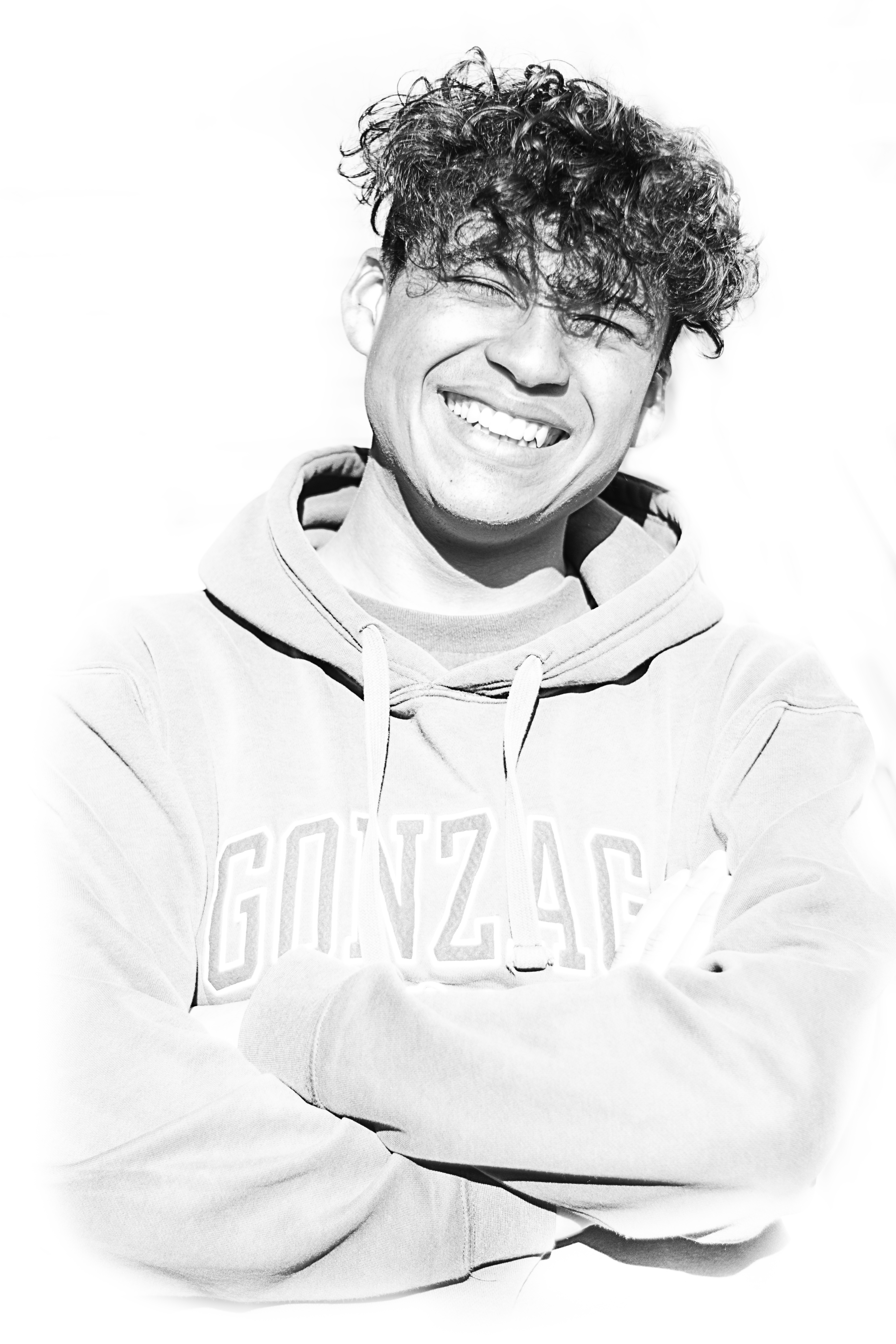 Black and white high-key studio portrait of a smiling young man in a hoodie