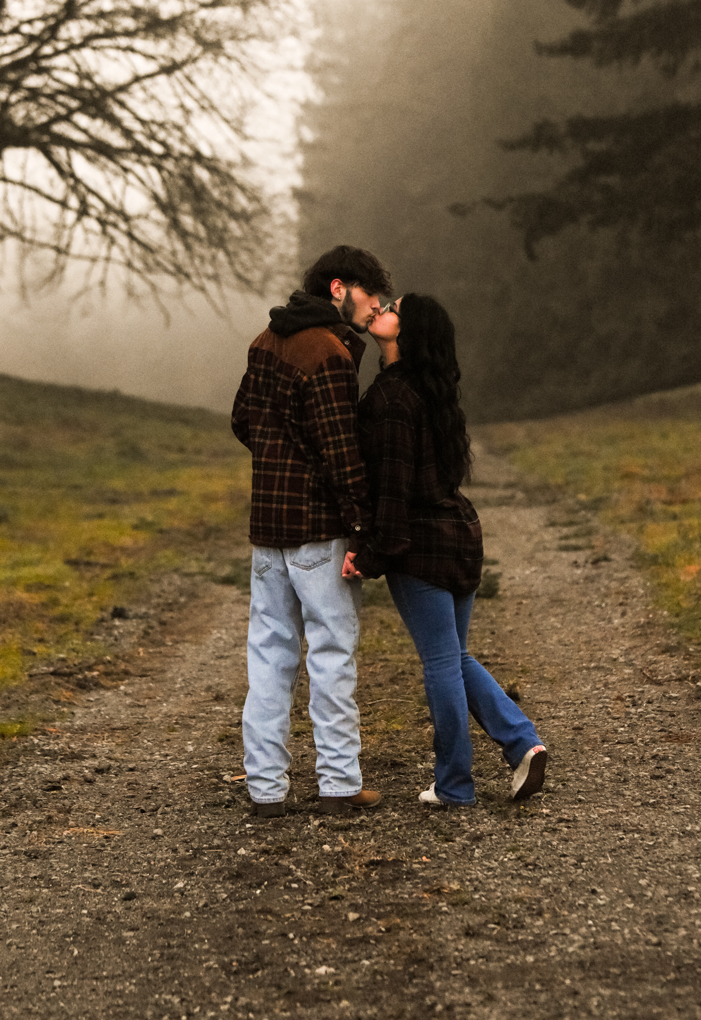 Couple standing close together on a foggy gravel path