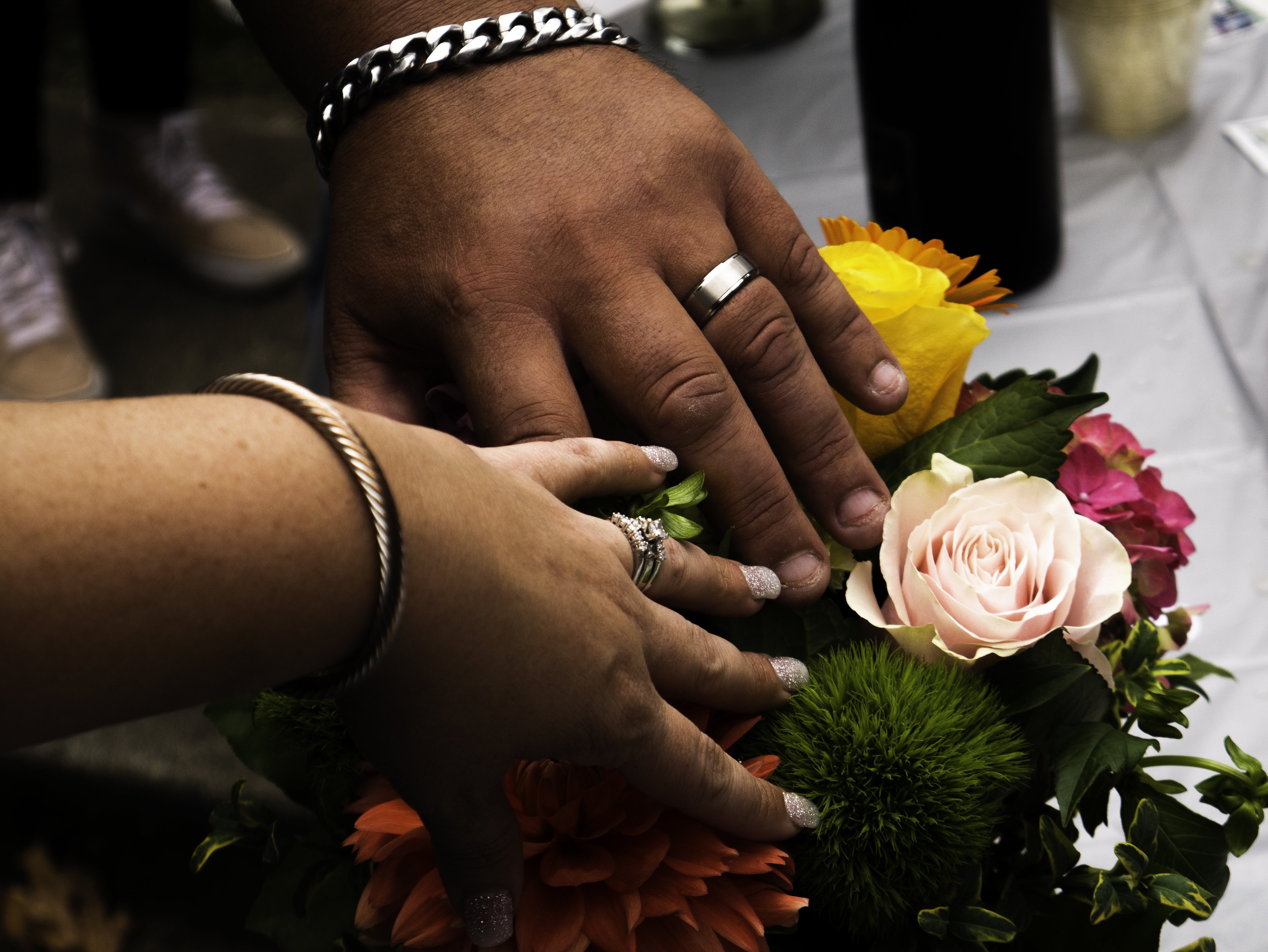 Couple's hands with wedding rings resting on a floral bouquet