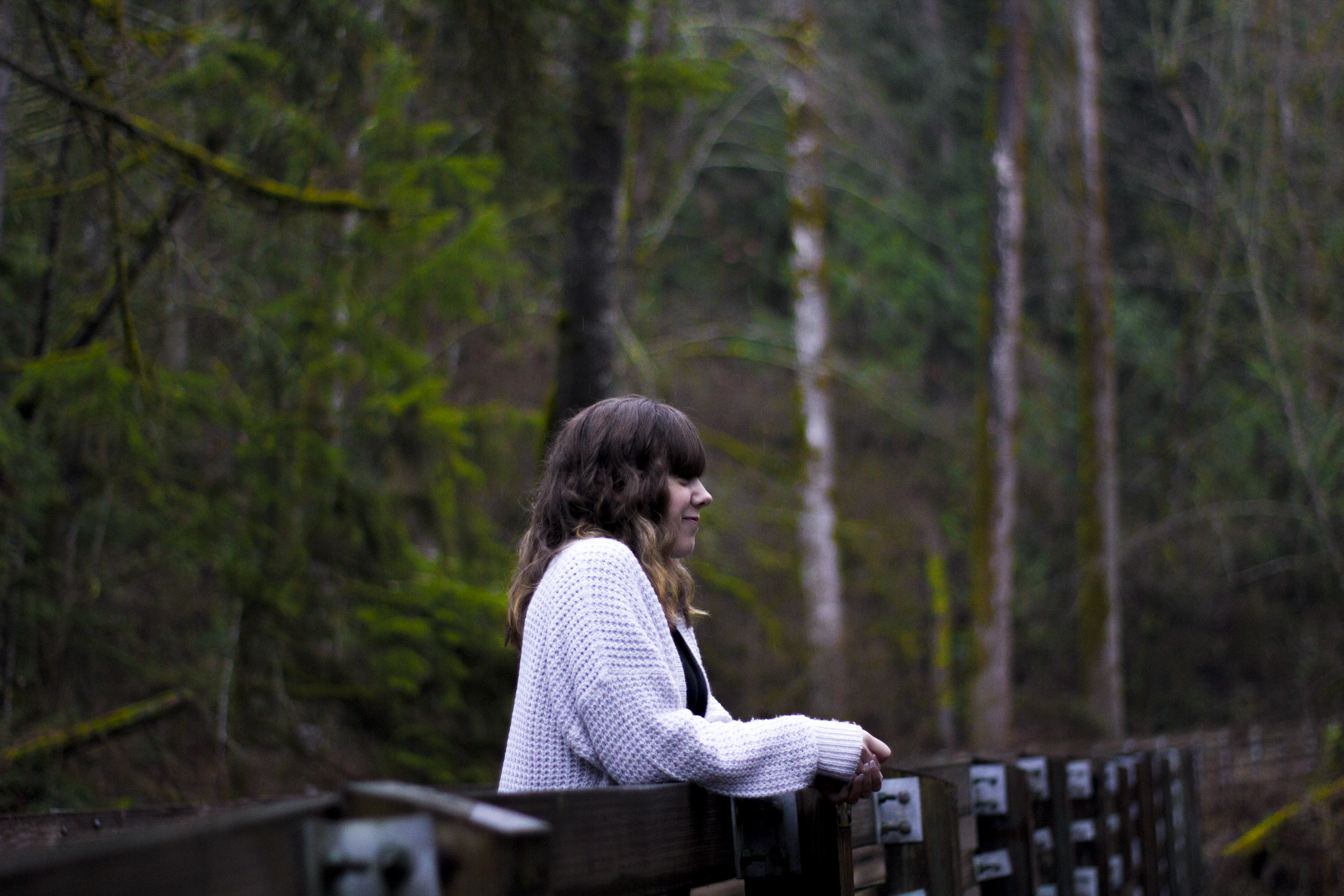 Senior portrait of a young woman seated among tall trees
