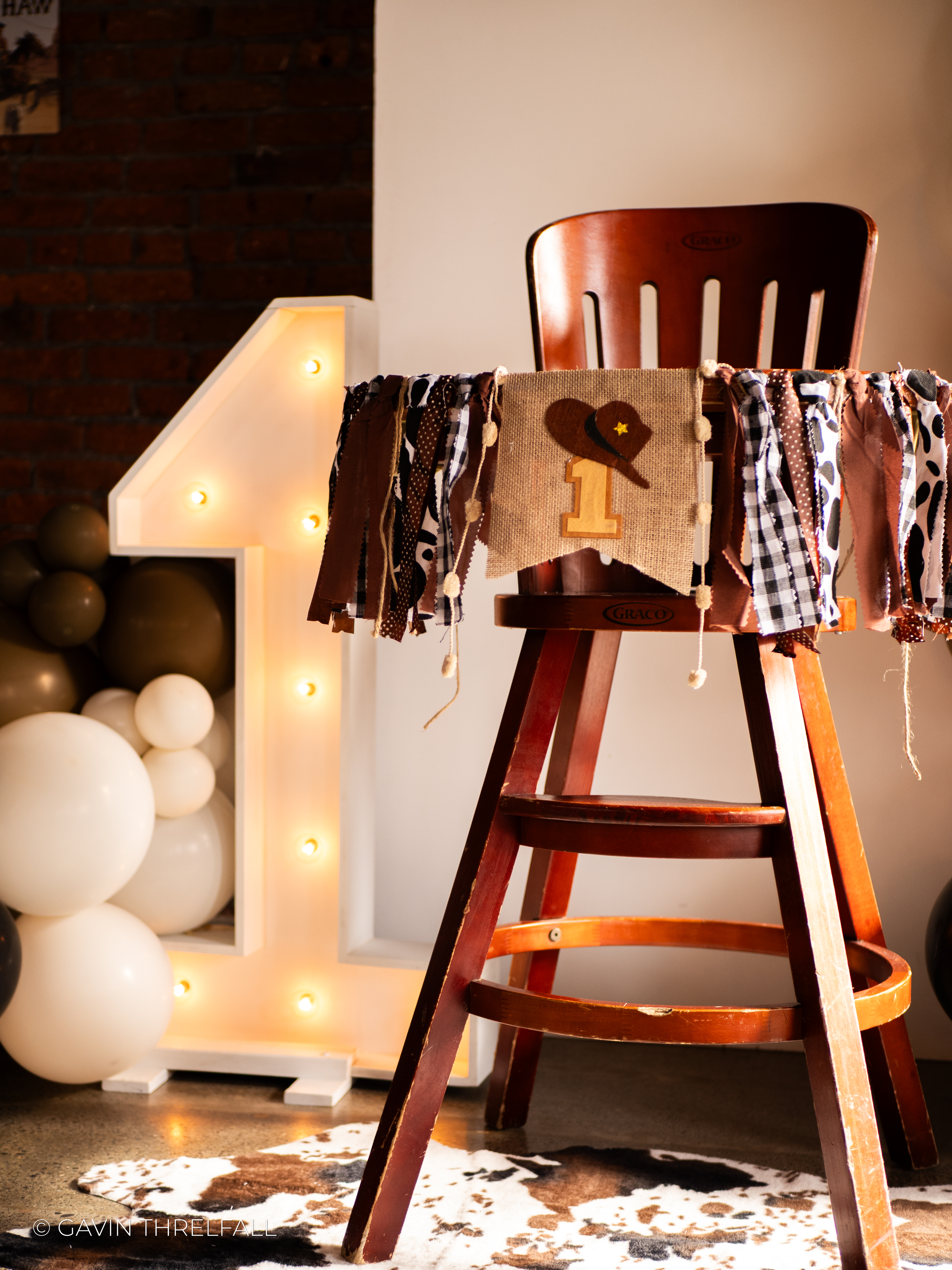 Lit marquee number one beside a decorated wooden highchair