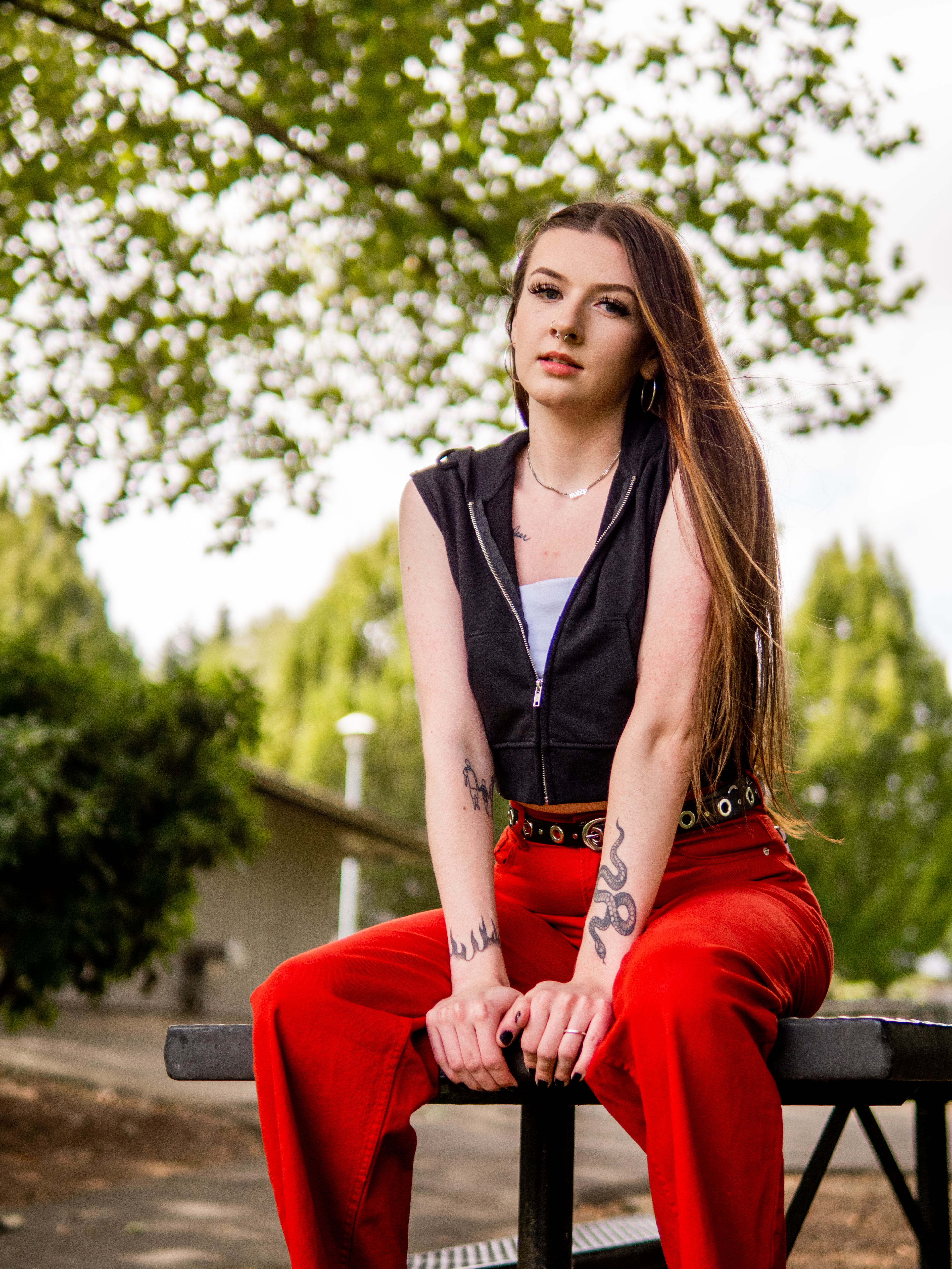 Senior in red trousers seated on a picnic table under a tree