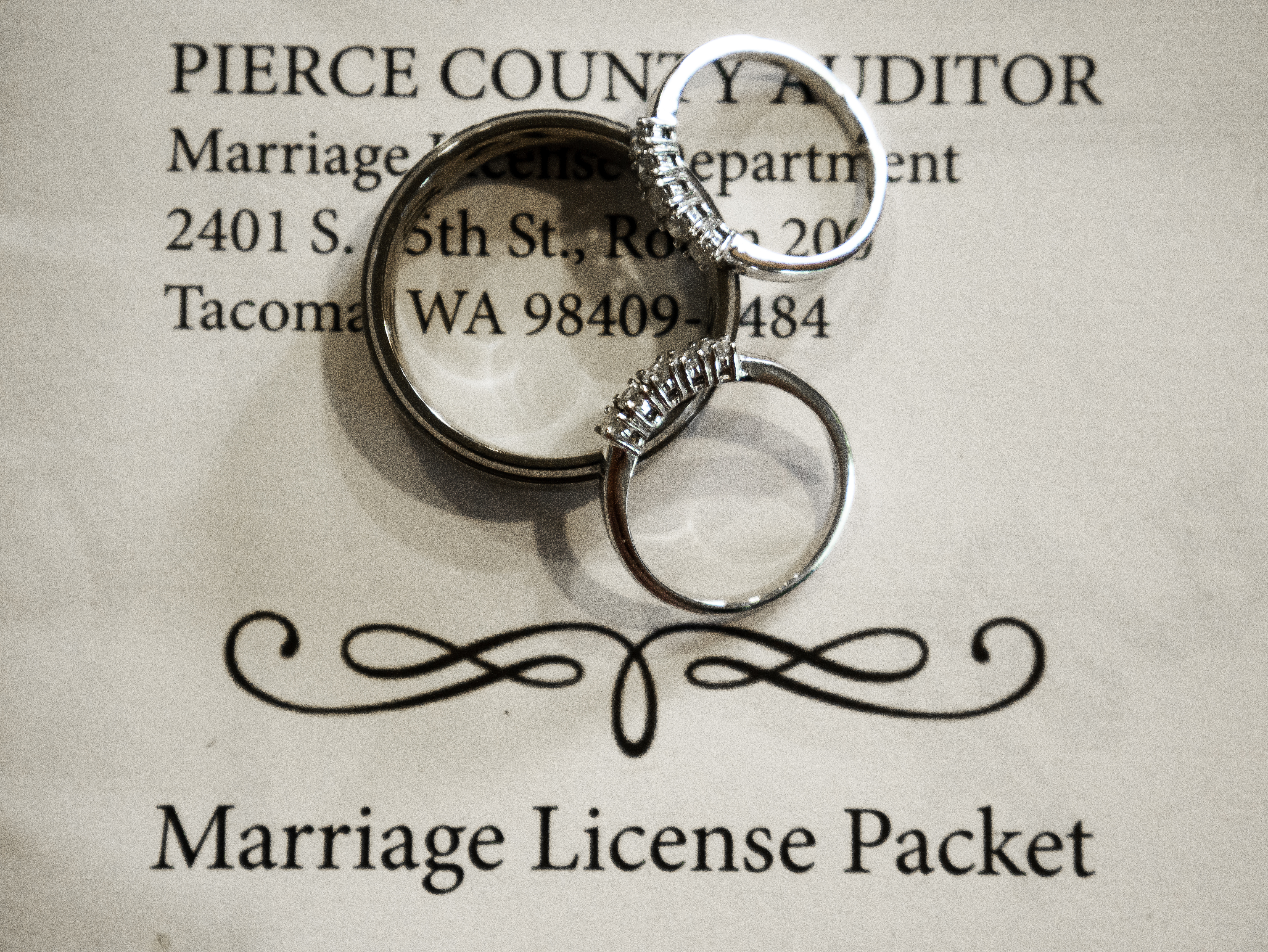 Wedding rings resting on a Pierce County marriage license packet