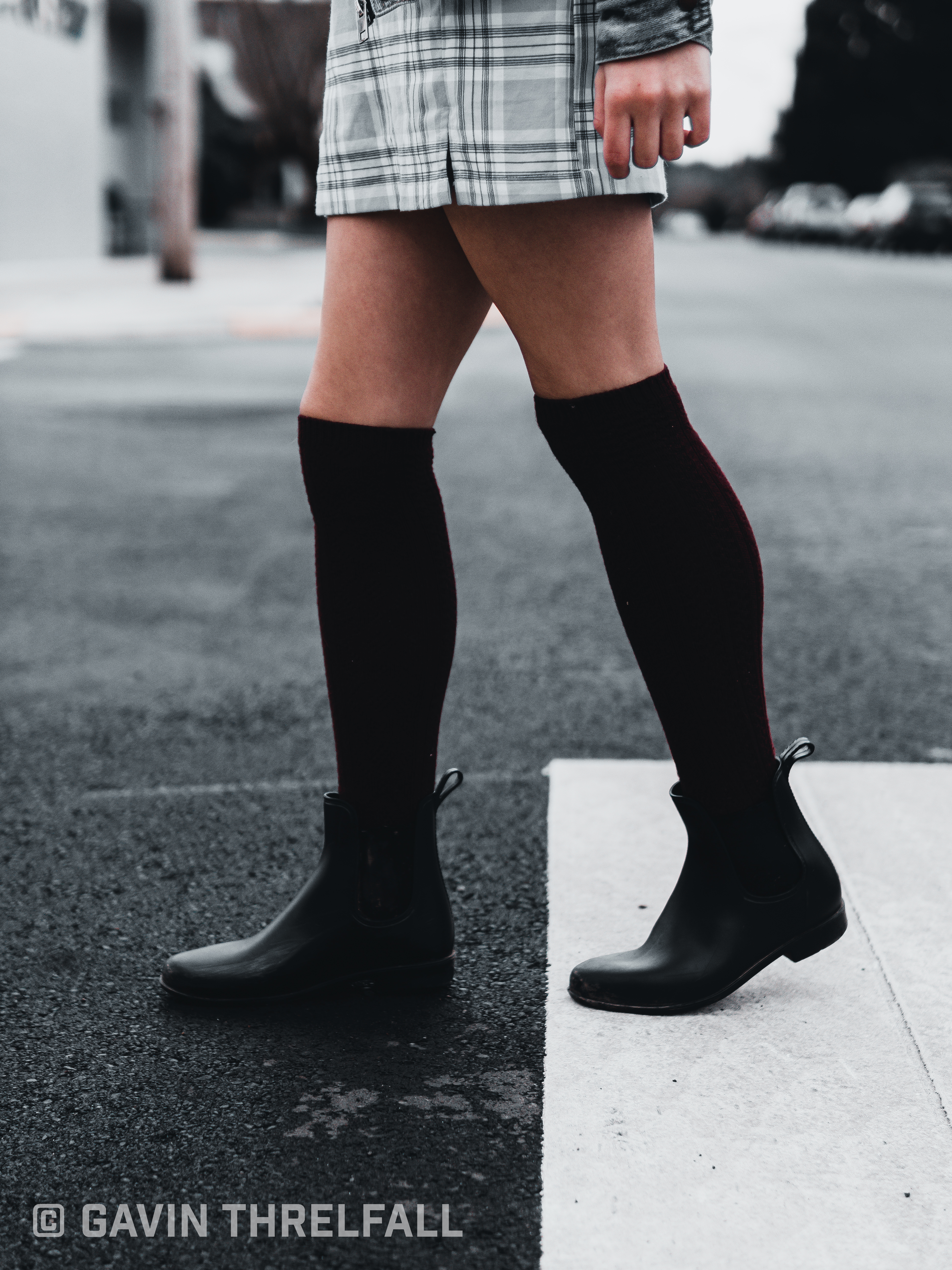 Detail of knee-high boots stepping across a painted crosswalk line