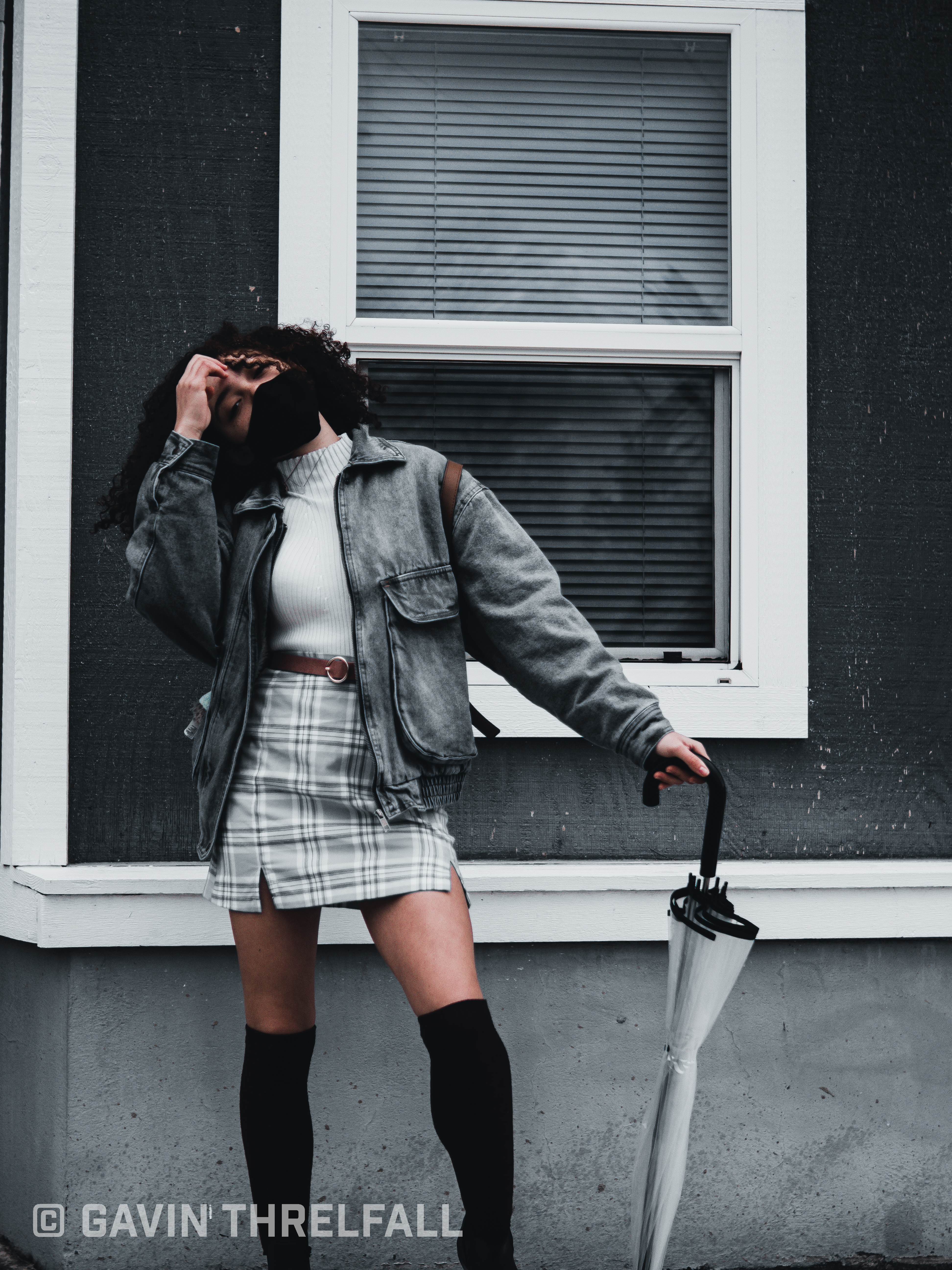 Model posing with an umbrella beside a storefront window