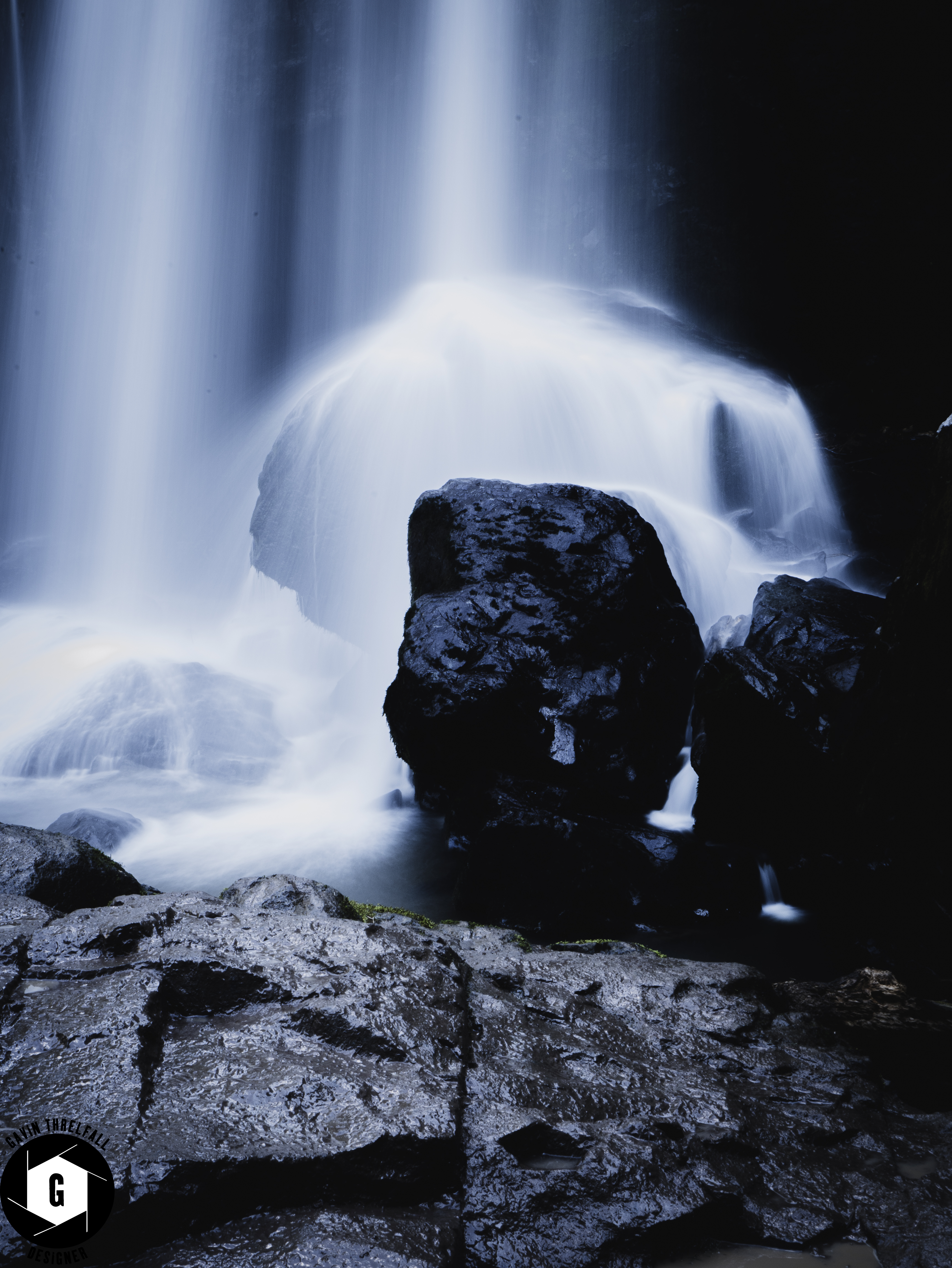 Silky long exposure of a waterfall flowing over dark boulders