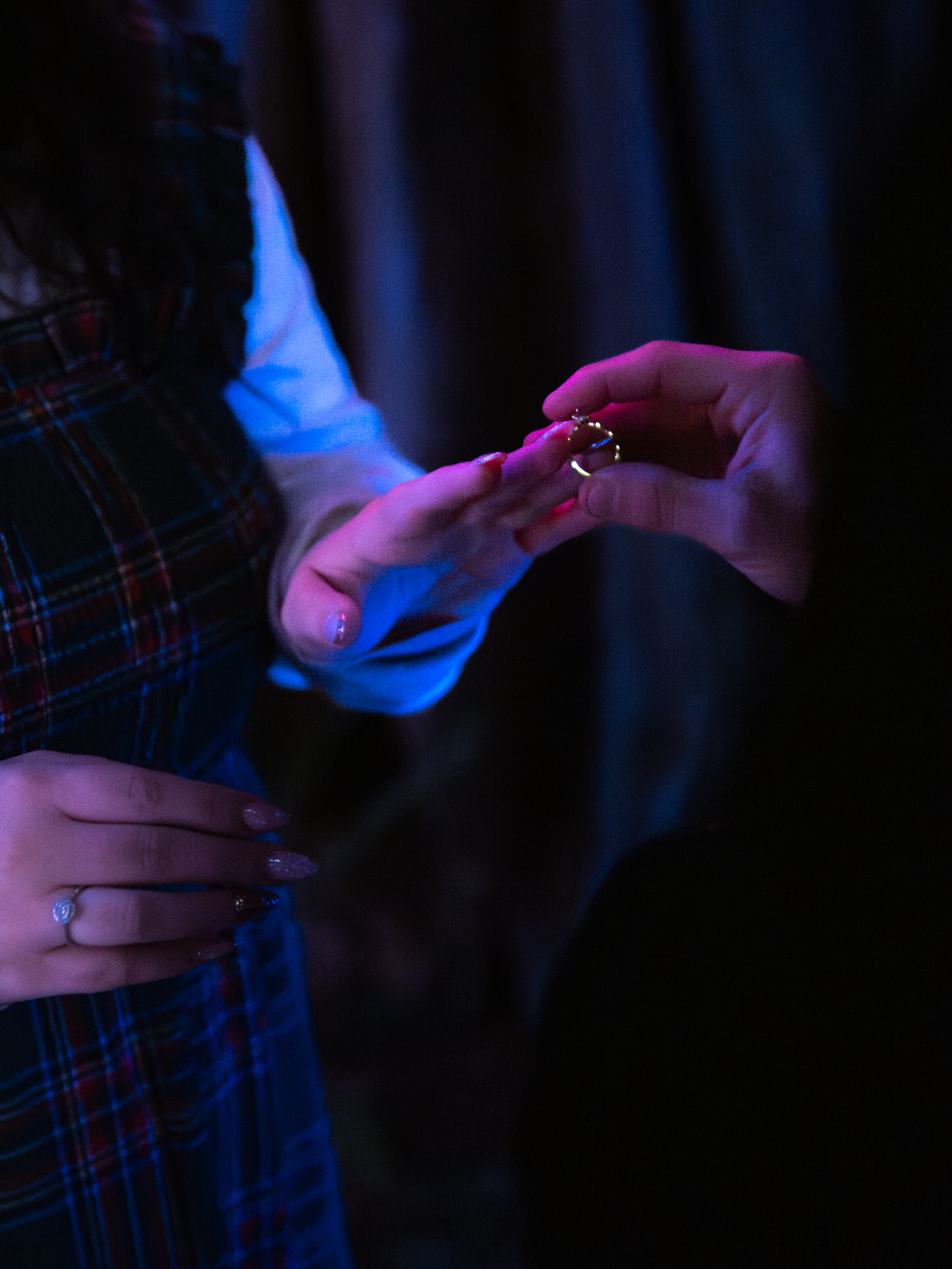 Close-up of a woman's engagement ring held in soft blue light