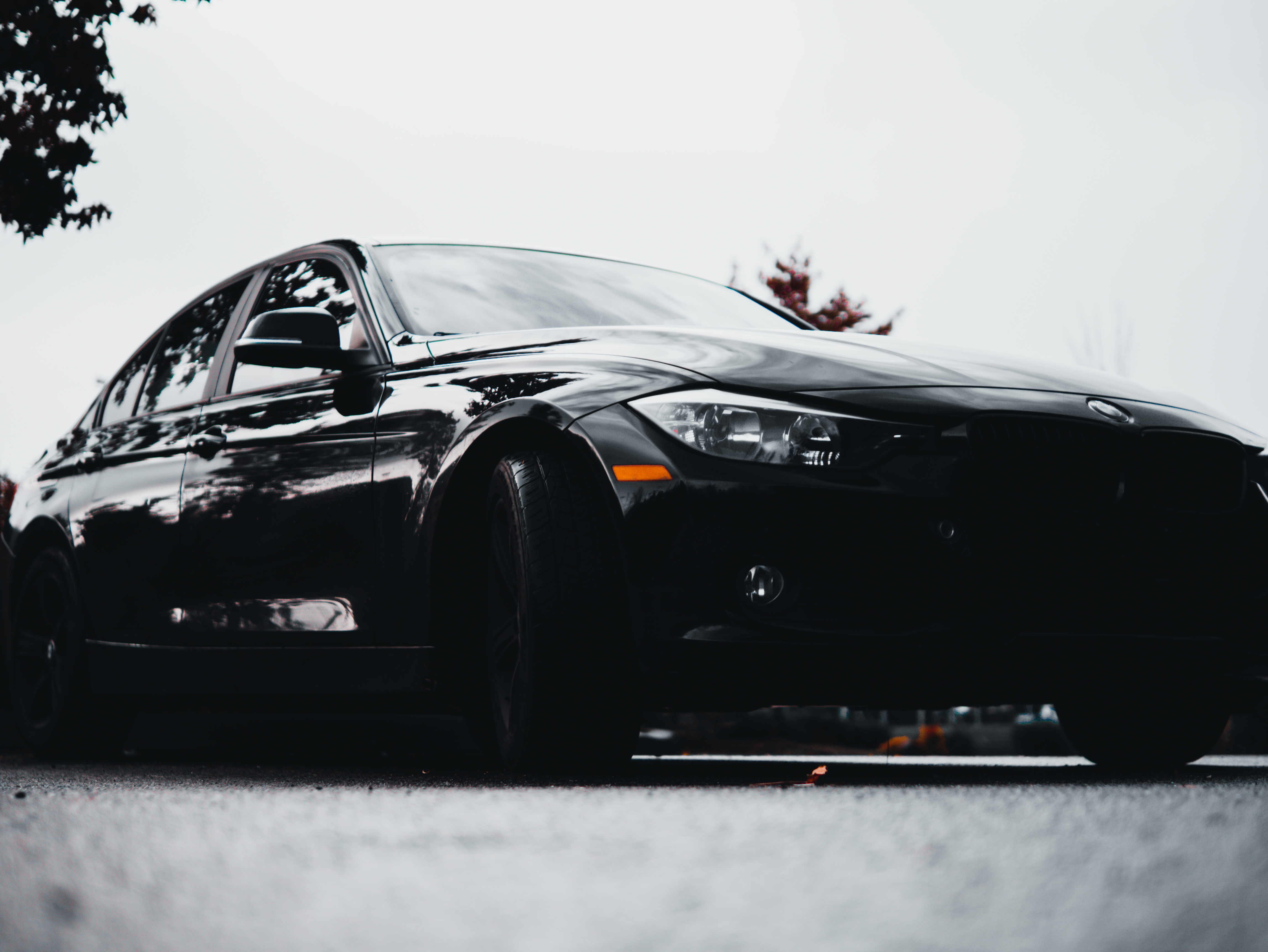 Black BMW sedan photographed in profile on wet asphalt