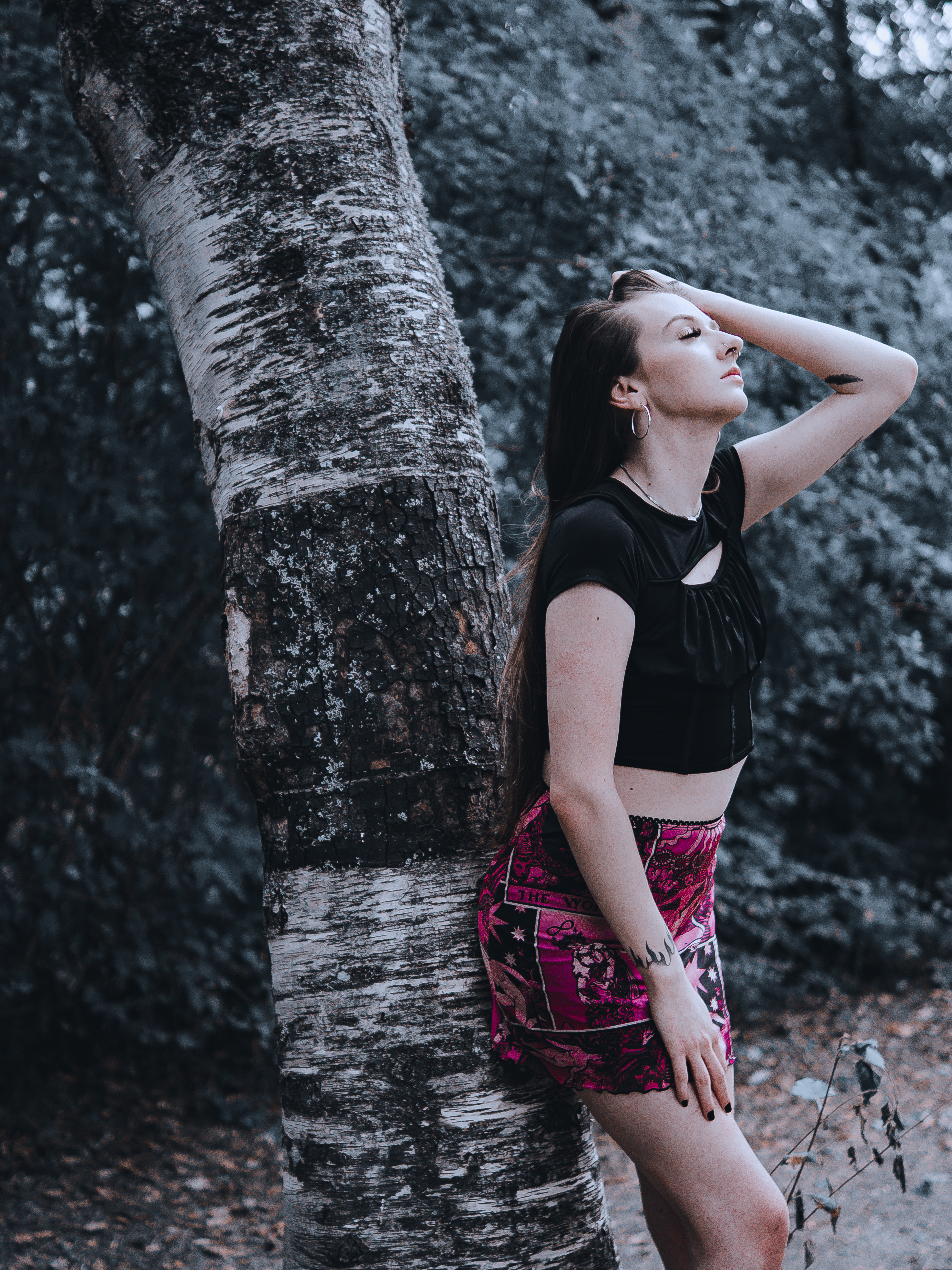 Senior leaning against a birch tree in a winter grove