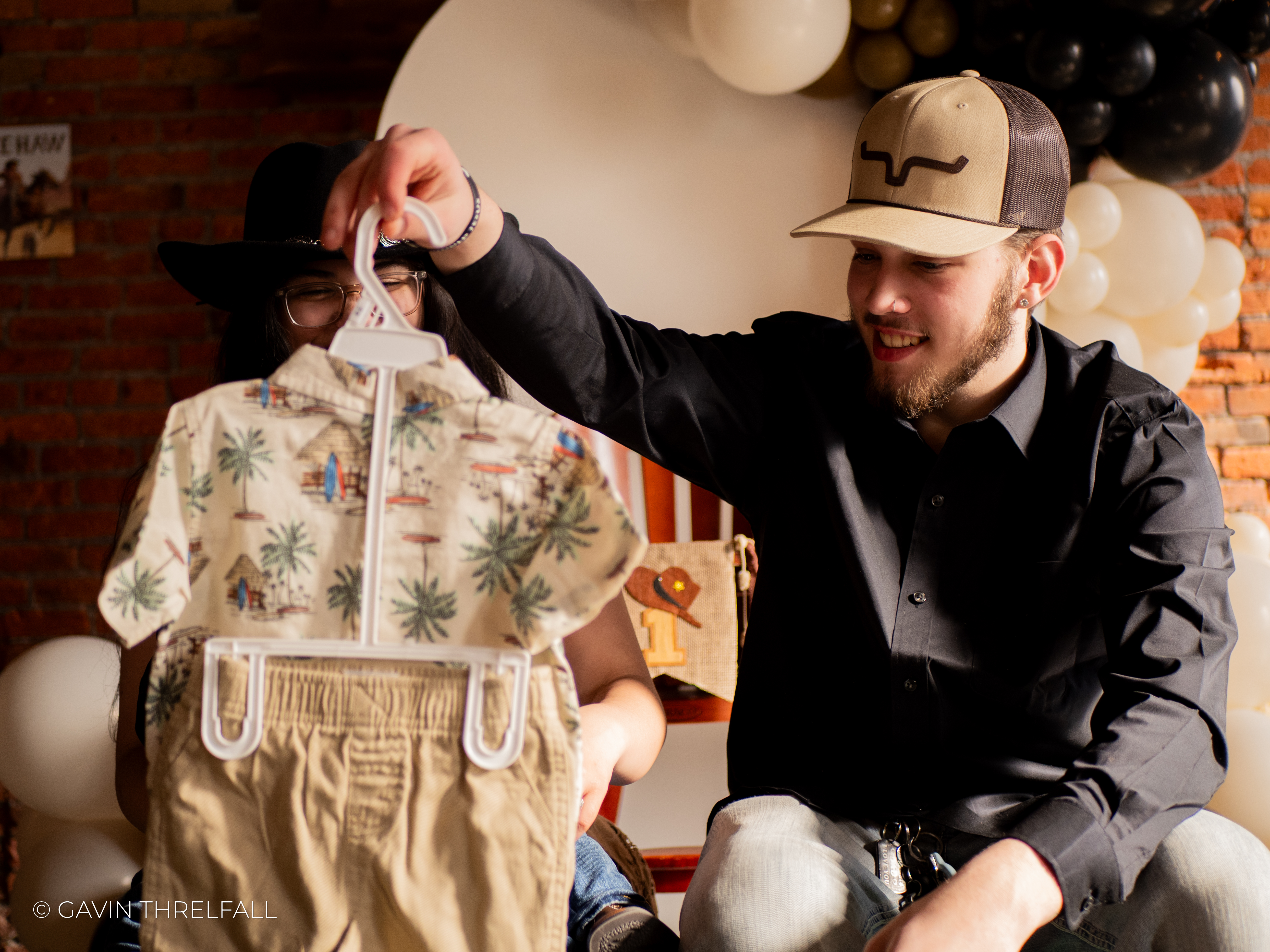 Father showing a toddler's western outfit at a birthday party