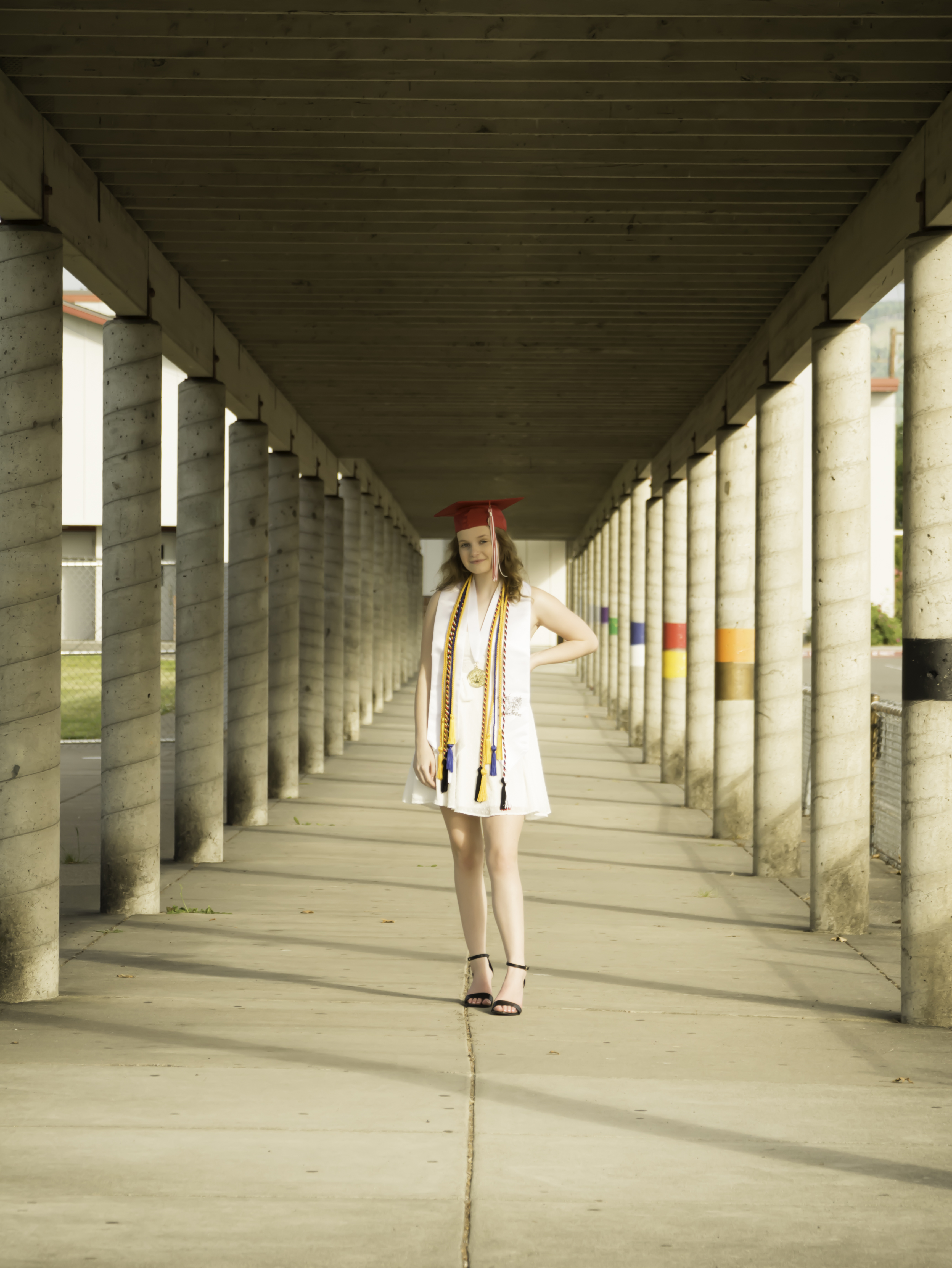 Graduate walking toward the camera through a covered campus walkway