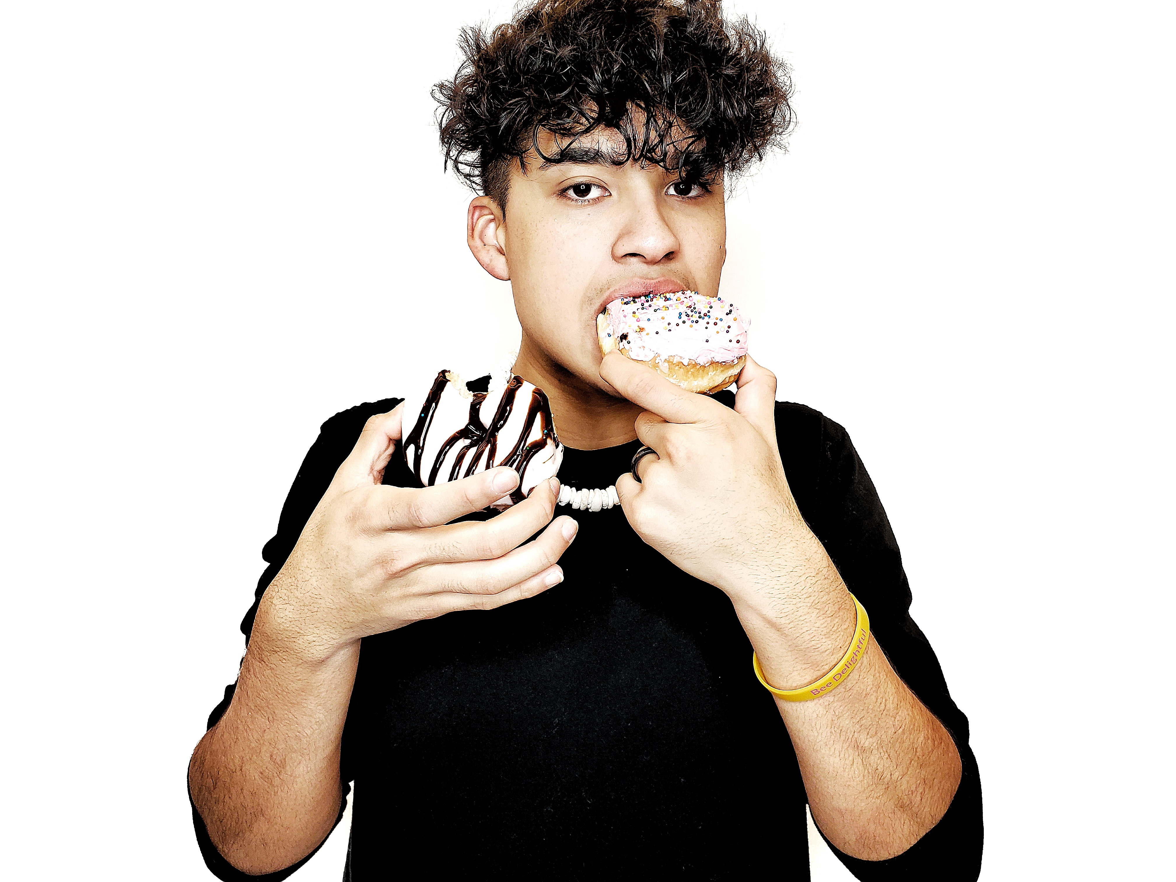 Young man in a studio taking a bite of a frosted donut