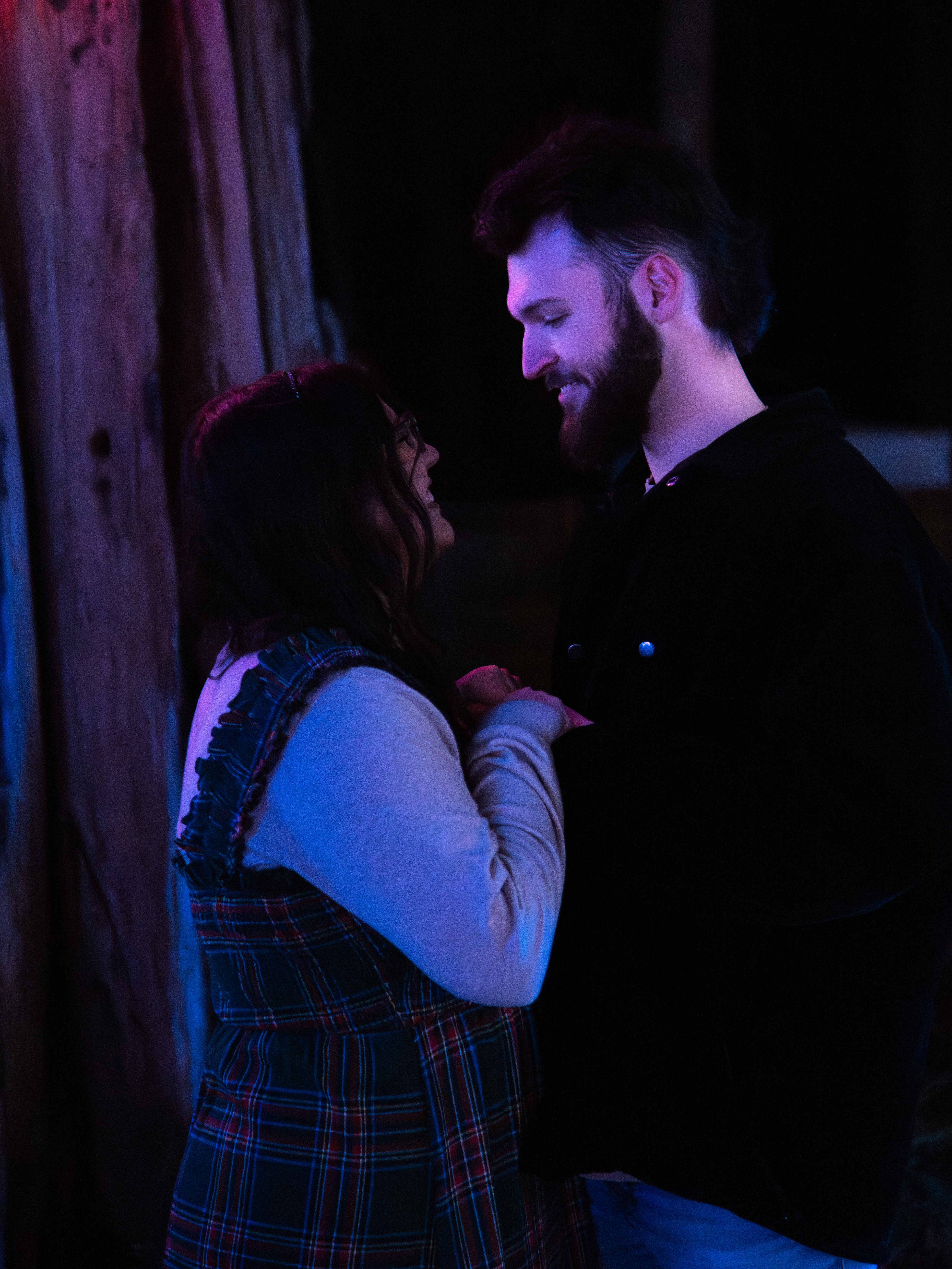 Engaged couple laughing together under purple and blue light