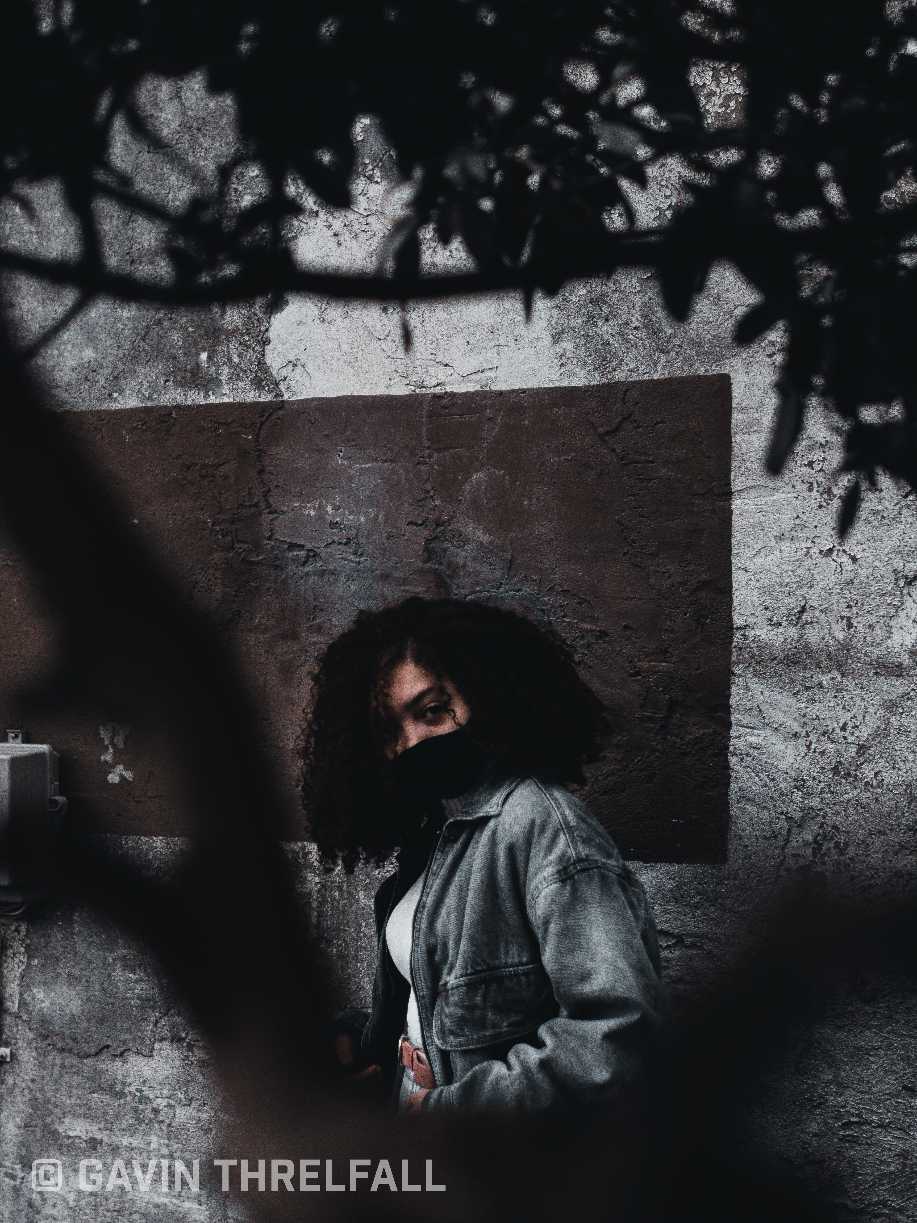 Model against a wall with tree shadows falling across the frame